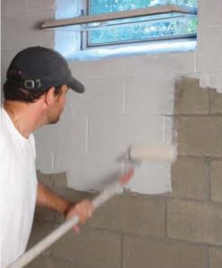 armorlock basement waterproofer in white being applied by man to wall